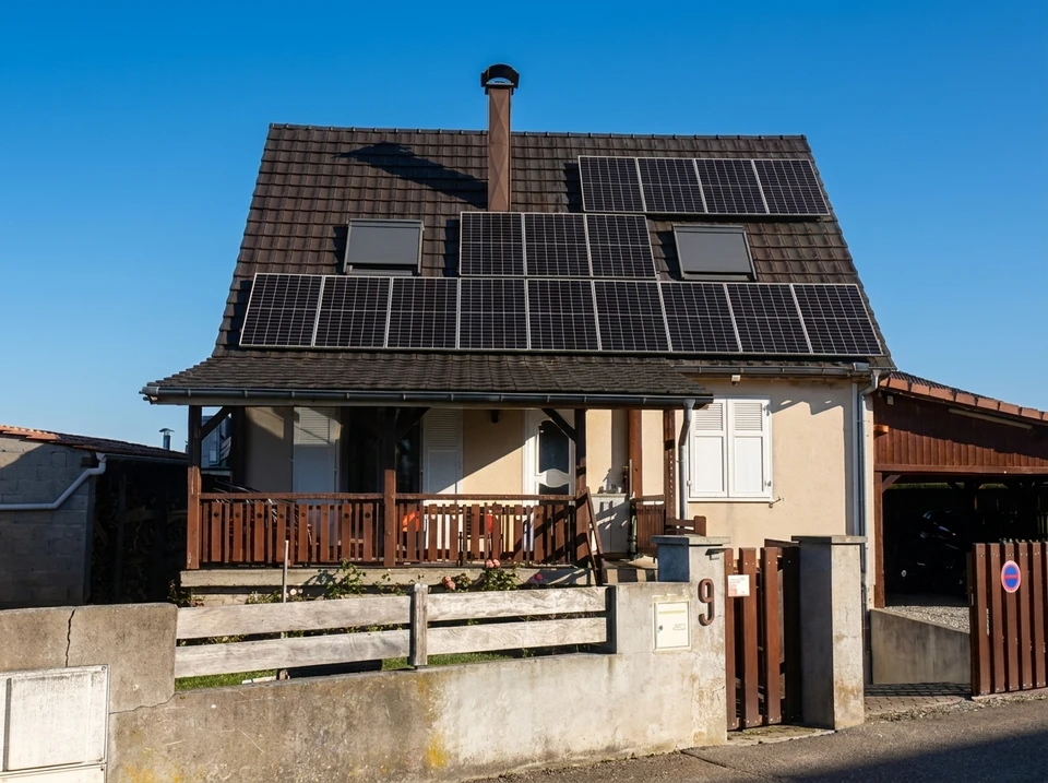 Ouvrier en combinaison de protection bleue appliquant de l'isolant par projection dans une structure en bois